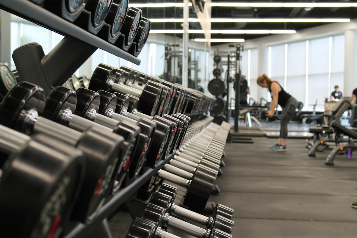 Rows of paired hexagonal and round dumbbells on tiered gym racks